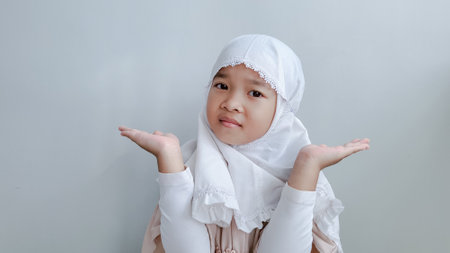 Asian young girl in hijab posing greeting hand gesture. Ramadhan and eid al fitr concept.の写真素材