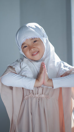 Asian young girl in hijab posing greeting hand gesture. Ramadhan and eid al fitr concept.の写真素材