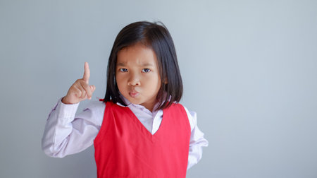 Image of Asian child posing on gray background. pointing finger up.の写真素材