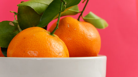 Ripe tangerines with leaves in a white bowlの写真素材