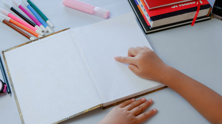 Close-up by the hand of a girl pointing to the white blank page of notebook with her finger.  mockup concept.の写真素材