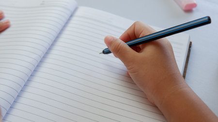education, childhood, people, homework and school concept - student girl with book writing to notebook at homeの写真素材