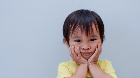 potrait of cute little asian boy holding his cheeks with his hands as suffering from toothache.の写真素材