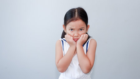 Portrait of little Asian girl bad mood failure isolated over gray backgroundの写真素材