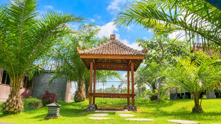 A Gazebo called Joglo around the palm trees and grass. A comfort place for relaxing and chat casually with family or friend.の写真素材