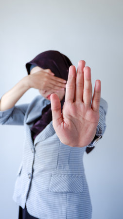 People, body language. Young Muslim woman covers eyes with palm and doing stop gesture, tries to hide from everybody. I don't want to see, feels ashamed or scared.の写真素材