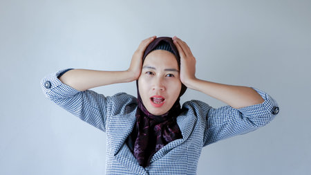 Young beautiful Asian woman wearing formal hijab outfit over gray isolated background suffering from...