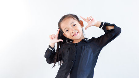 Closeup happy cute little Asian girl in black dress smiling over gray background