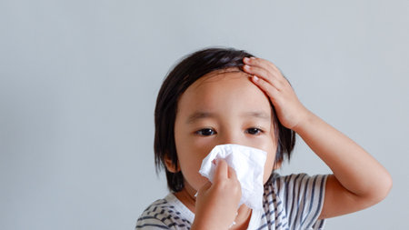 cute Asian child holding tissue and his head for healthcare conceptの写真素材