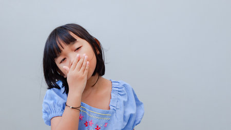 Asian kid girl toothache. Kid suffering from toothache. Asian child hand on mouth face as suffering from facial pain, mumps toothache. Dental health care.の写真素材