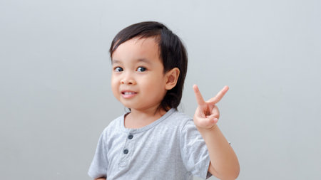 asian boy showing up two fingers, the peace symbol.の写真素材