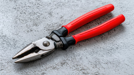 This image features a pair of pliers with a silver metallic finish and red rubber grips, set against a gray textured surface, ideal for tools, repairs, and DIY projects.の素材
