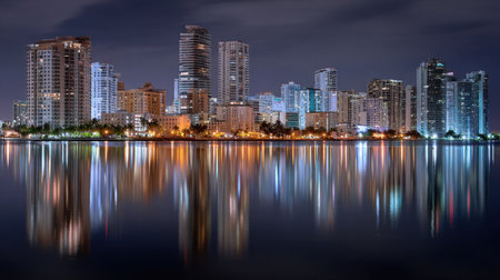 A breathtaking nighttime cityscape featuring illuminated buildings reflecting off calm waters. The serene scene captures urban beauty and tranquility.の素材