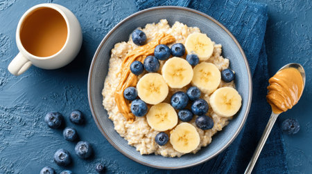 A vibrant bowl of oatmeal topped with sliced bananas, fresh blueberries, and a drizzle of peanut butter, accompanied by a cup of coffee, perfect for a healthy breakfast.の素材