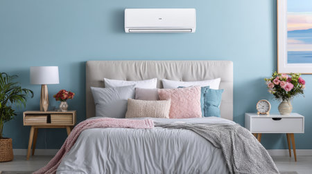 This modern bedroom features a soothing blue wall, an air conditioning unit, and a variety of cozy bedding and decorative pillows, creating a serene retreat.の素材