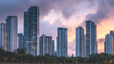 A captivating urban skyline featuring towering buildings illuminated by a colorful sunset. The serene park below enhances the cityの素材