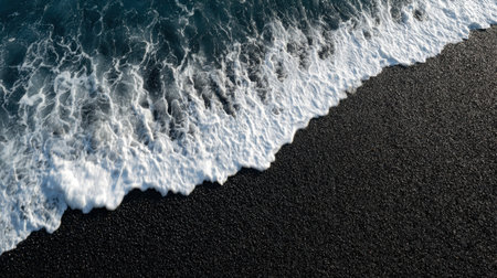 This stunning aerial photograph captures the gentle waves of the ocean breaking on a unique black sandy beach, creating mesmerizing foam patterns.の素材