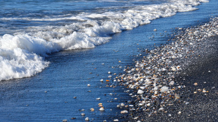 A captivating view of gentle waves washing up on a black sand beach, scattered with colorful shells and pebbles, reflecting the beauty and tranquility of nature.の素材