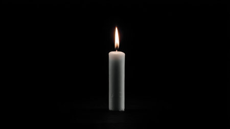 A white candle burns brightly against a dark background, symbolizing peace and serenity. Its gentle light creates a calming atmosphere suitable for relaxation or meditation.の素材