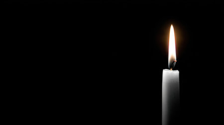A single white candle stands tall against a dark background, its flame flickering gently. This image conveys tranquility, warmth, and serenity, inviting reflection.の素材