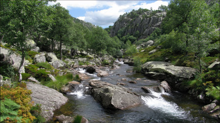 A picturesque view of a serene river winding through a lush green landscape, surrounded by rocky outcrops and scenic mountains under a vibrant sky.の素材