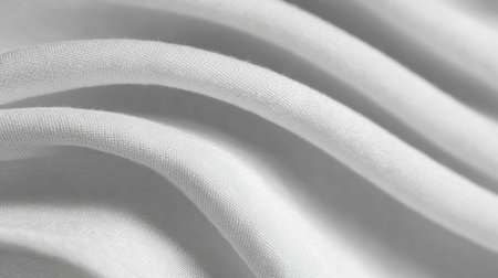 Close-up view of smooth white fabric showcasing elegant folds and delicate texture, perfect for minimalistic backgrounds or textile design inspiration.の素材