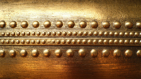 This close-up image features a luxurious gold textured surface adorned with round studs and horizontal lines, perfect for design inspiration and elegance.の素材