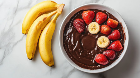 A tempting dessert bowl filled with rich chocolate dip, topped with vibrant strawberries and banana slices, perfect for a sweet indulgence.の素材