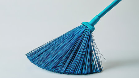 A vibrant blue broom with fine bristles sits on a light background, ideal for conveying cleanliness, household chores, and domestic organization.の素材