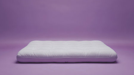 A soft white mattress rests on a smooth purple backdrop, creating a serene setting perfect for promoting comfort and relaxation in a bedroom environment.の素材