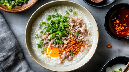 A warm bowl of savory porridge topped with minced meat, green onions, and a soft-boiled egg, perfect for breakfast or cozy meals.の素材