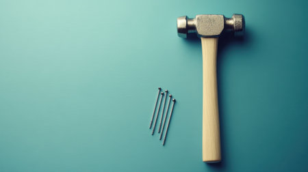 This image features a metal hammer with a wooden handle and several metal nails arranged neatly against a soft-colored background, perfect for DIY enthusiasts.の素材