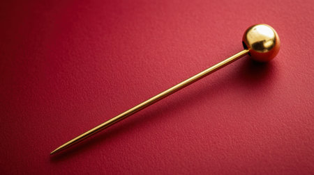 A stunning gold pin featuring a round head rests elegantly on a rich red background. Perfect for fashion accessories and decorative crafts, this image captures luxury and style in a minimalist design. Ideal for creative projects.の素材