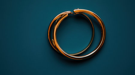 Stunning golden hoop earrings showcased against a vibrant teal background. This elegant jewelry piece embodies minimalist design, perfect for stylish women.の素材