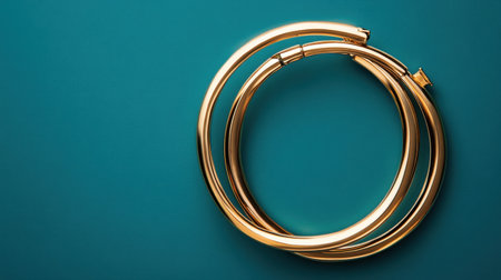 Capture the essence of luxury with these elegant gold hoop earrings set against a vibrant teal background. Ideal for jewelry lovers and fashion enthusiasts.の素材
