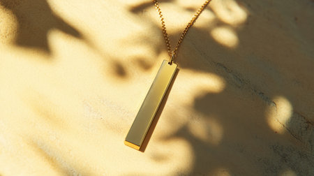 This image features an elegant gold pendant necklace resting on a textured surface, casting soft shadows, perfect for showcasing minimalist jewelry design.の素材