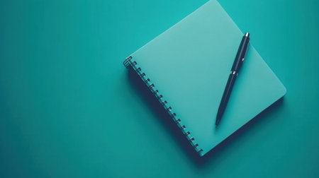 A visually appealing teal notebook paired with a sleek black pen rests on a solid teal background, perfect for inspiring creativity and organization.の素材