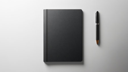 A sleek black notebook placed next to a stylish pen on a soft grey background, perfect for creative writing, planning, or note-taking in any environment.の素材