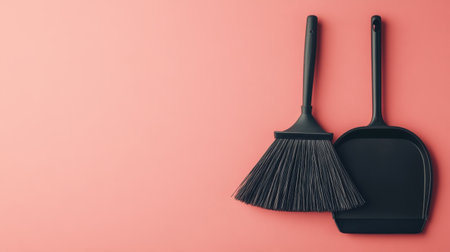 A modern composition of black cleaning tools including a broom and dustpan displayed on a vibrant pink background, ideal for design and cleaning themes.の素材