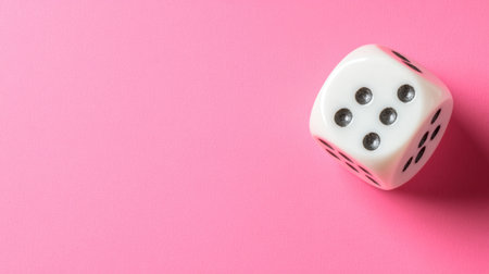 A single white dice with black dots rests on a soft pink background, symbolizing chance and fun in games and leisure activities. Perfect for various projects!の素材