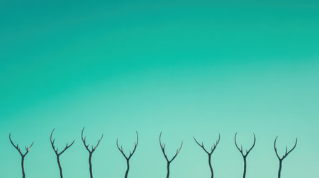 This striking image features silhouetted trees with unique antler-like branches set against a tranquil turquoise sky. Perfect for nature-themed projects.の素材