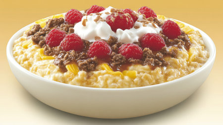 A vibrant bowl of creamy oatmeal features fresh raspberries, crumbled nuts, and whipped cream, offering a delicious and visually appealing breakfast option.の素材