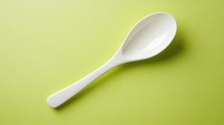A stylish white ceramic spoon placed elegantly on a vibrant green background, perfect for showcasing culinary creations and modern kitchen designs.の素材