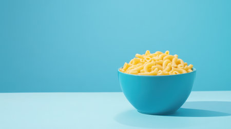 This image features a bright blue bowl filled with cheesy pasta, set against a vibrant minimalist background. The clean and colorful presentation makes it ideal for food-related projects.の素材