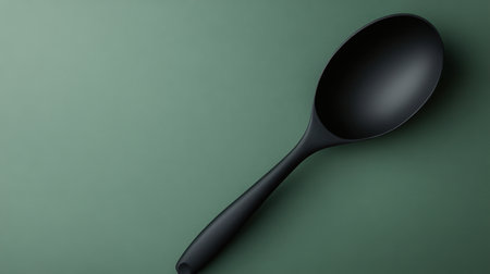 Elegant black spoon rests on a textured green surface, showcasing minimalist style for culinary and home decor themes. Ideal for creative projects.の素材