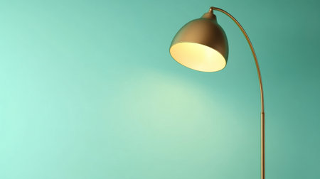A stylish floor lamp with a smooth golden arc and a warm light shade perfectly illuminates a striking turquoise wall in a modern interior setting.の素材