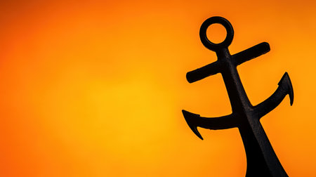 A striking silhouette of an anchor beautifully framed against a dramatic sunset sky, showcasing vibrant orange and yellow hues, ideal for nautical themes.の素材