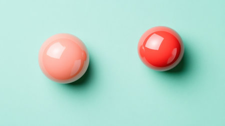 A pair of glossy spheres in vibrant red and coral resting on a soft mint background, ideal for modern design projects or abstract art concepts.の素材