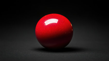 This striking polished red sphere stands out against a black background, showcasing a beautiful reflection and vibrant color, ideal for artistic designs.の素材