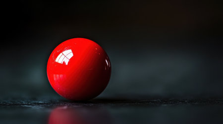 A striking image of a single glossy red ball resting on a dark surface, emphasizing reflections and soft highlights, perfect for art and design applications.の素材